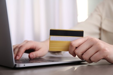 Photo of Online payment. Woman with laptop and credit card at grey table, closeup