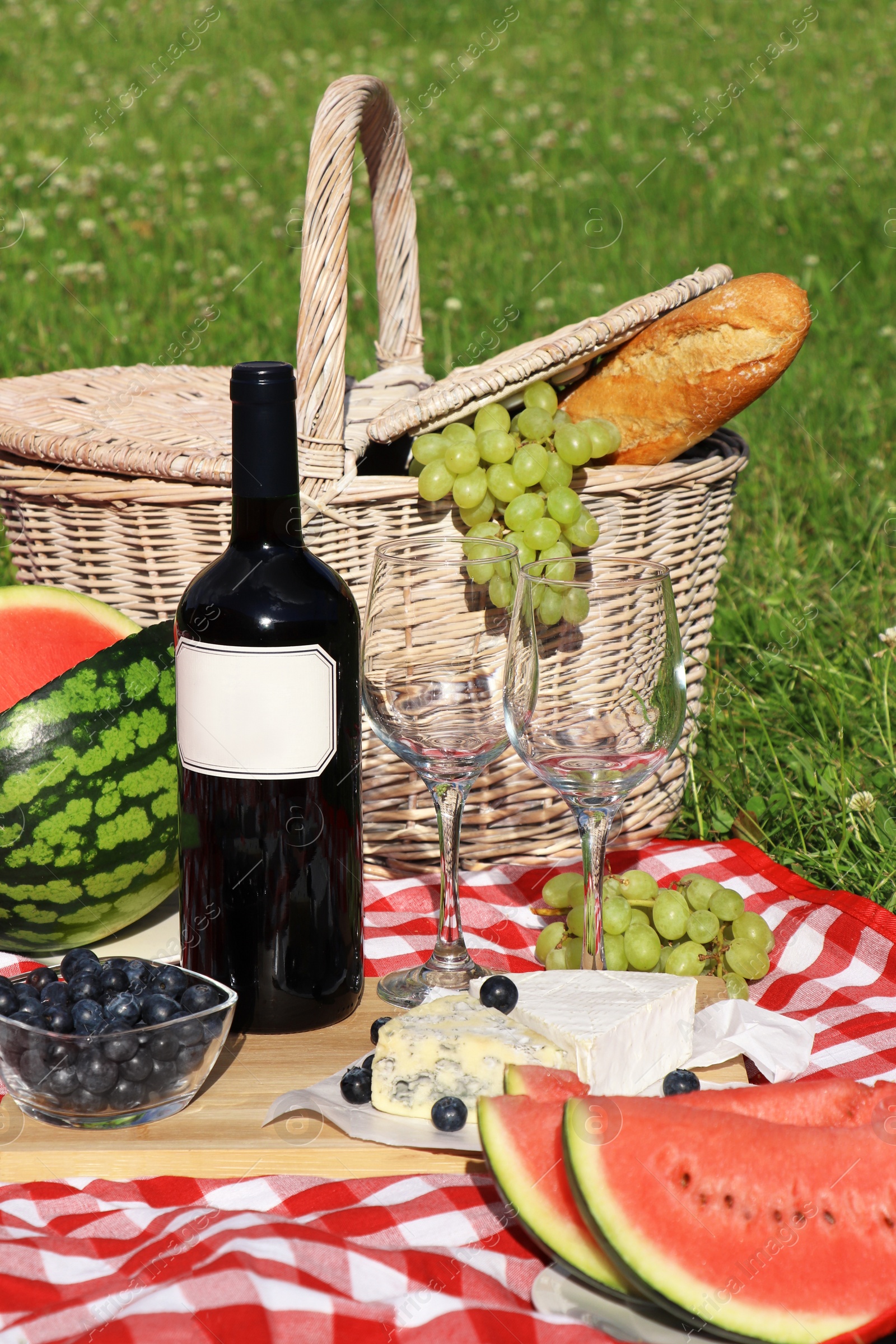 Photo of Picnic blanket with delicious food and wine outdoors on summer day