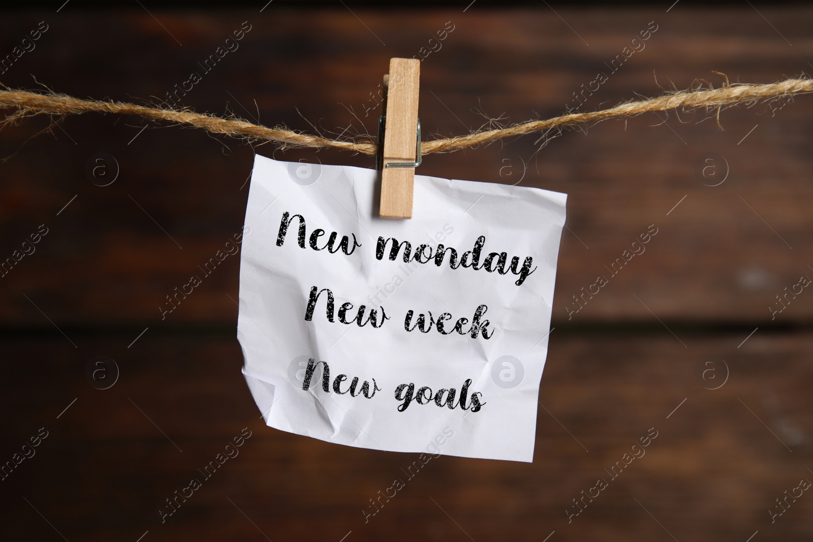 Image of New Monday, New Week, New Goals - motivational quote. Crumpled paper note with text against wooden background