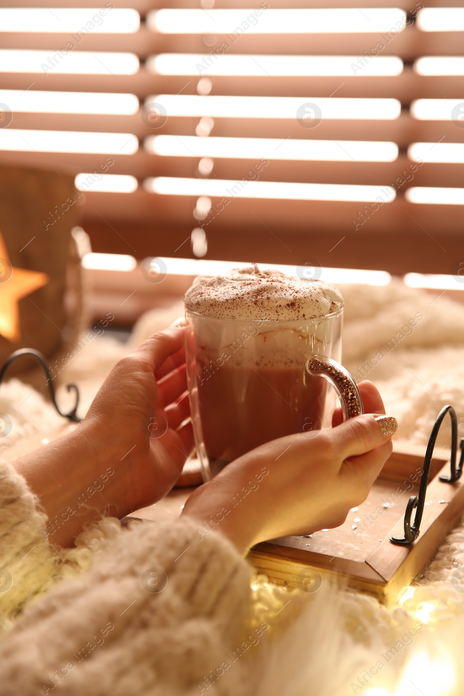 Photo of Woman holding cup of delicious drink with whipped cream indoors, closeup. Christmas celebration