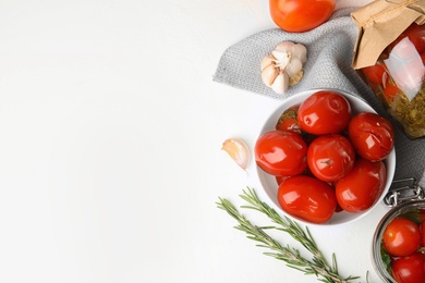 Flat lay composition with pickled tomatoes in glass jars on white table