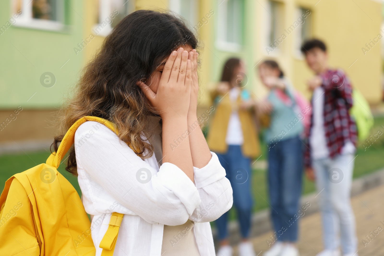 Photo of Teen problems. Group of students pointing at upset girl outdoors, selective focus