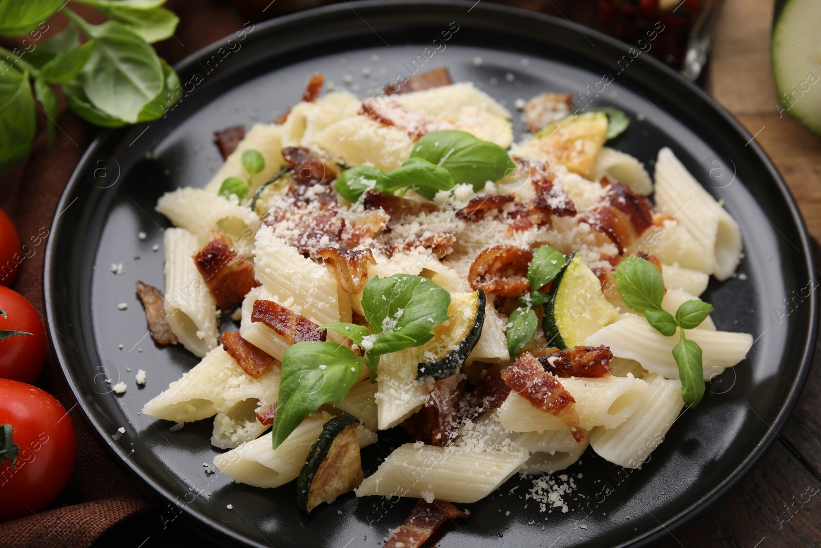 Photo of Tasty pasta with bacon and basil on wooden table, closeup