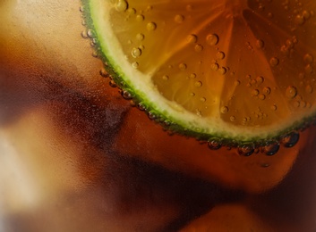 Photo of Glass of refreshing soda drink with ice cubes and lime, closeup