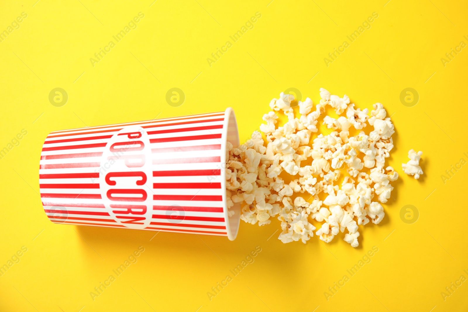 Photo of Cup with fresh tasty popcorn on color background, top view. Cinema snack