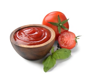 Photo of Tasty ketchup in wooden bowl, fresh tomatoes, peppercorns and basil isolated on white