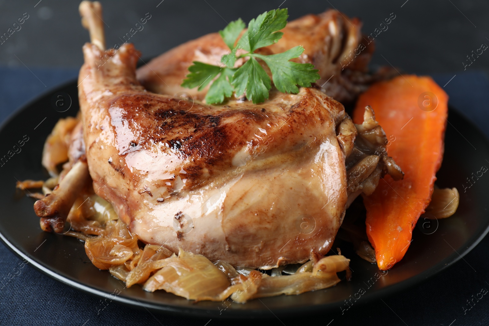 Photo of Tasty cooked rabbit meat with vegetables and parsley on table, closeup