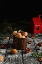 Photo of Homemade walnut shaped cookies with boiled condensed milk, fir branches and cones on wooden table