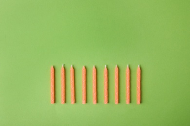 Photo of Orange birthday candles on green background, top view with space for text