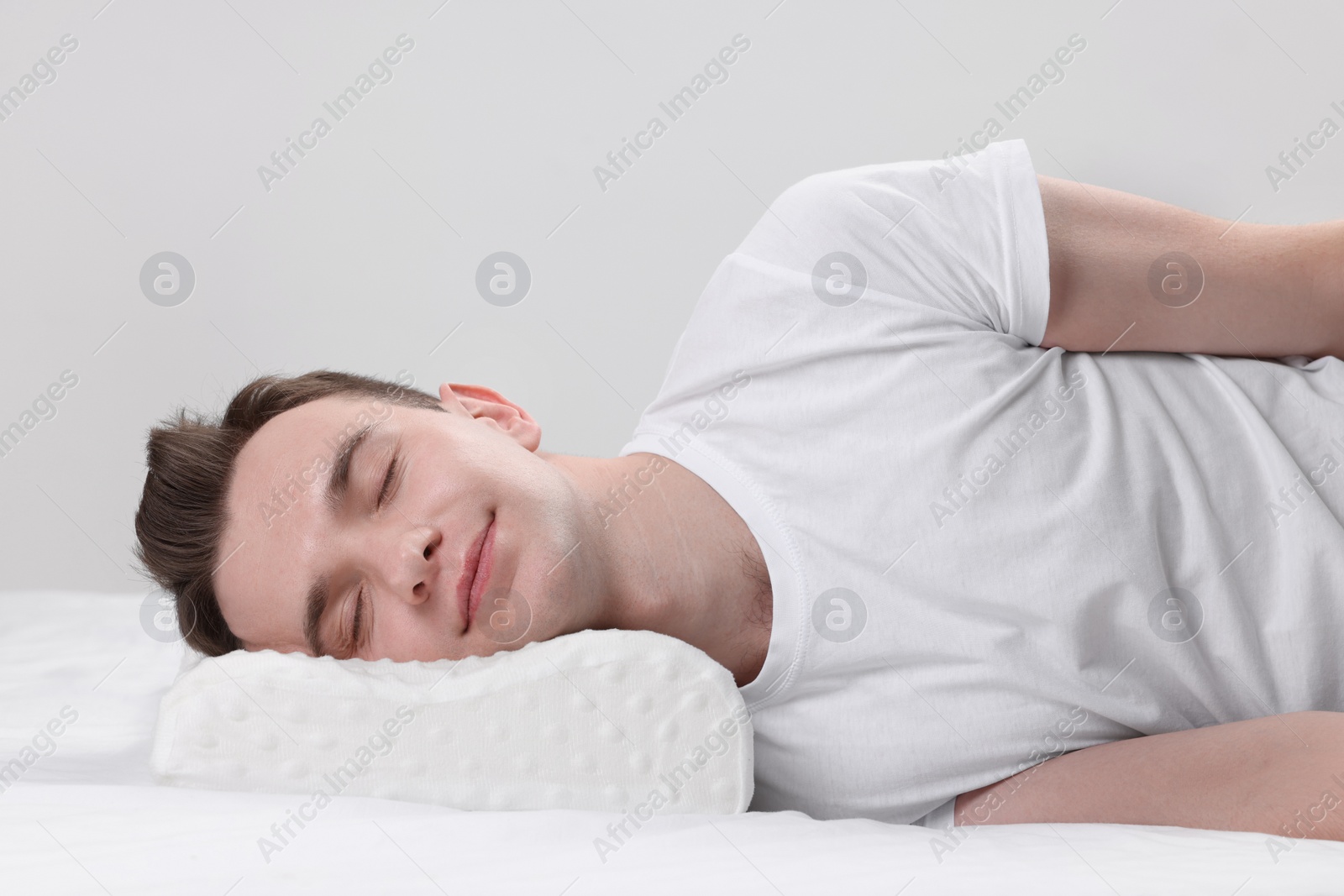 Photo of Man sleeping on orthopedic pillow against light grey background