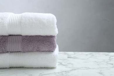 Stack of folded terry towels on white marble table, closeup. Space for text