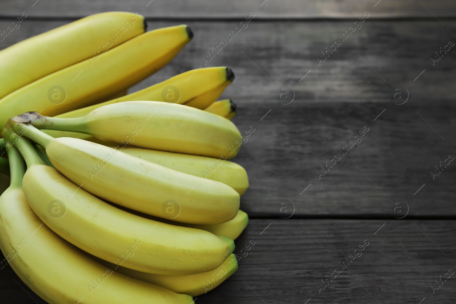 Photo of Ripe yellow bananas on wooden table. Space for text
