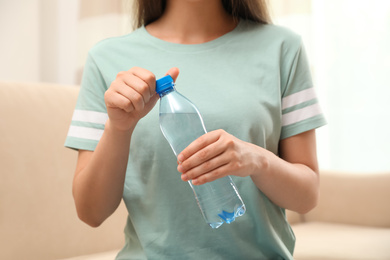 Photo of Woman with bottle of fresh water indoors, closeup