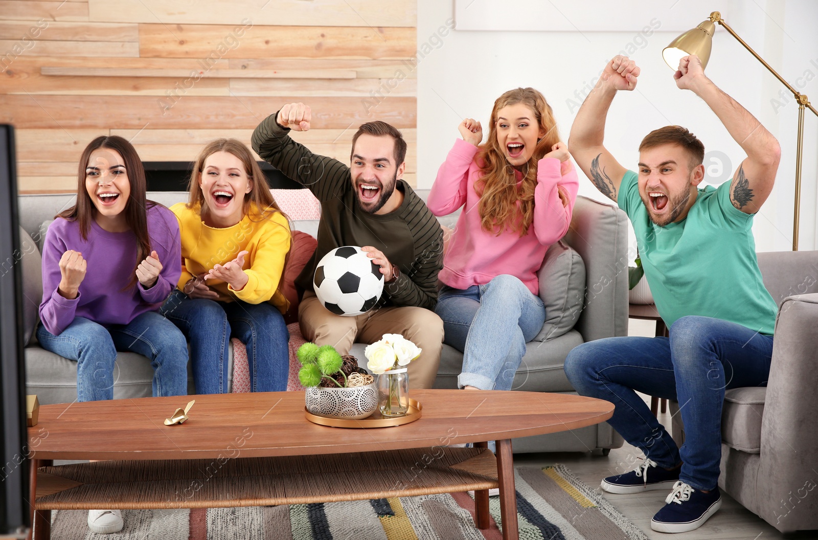 Photo of Group of friends celebrating victory of favorite soccer team in living room