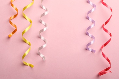 Photo of Colorful serpentine streamers on pink background, flat lay. Space for text