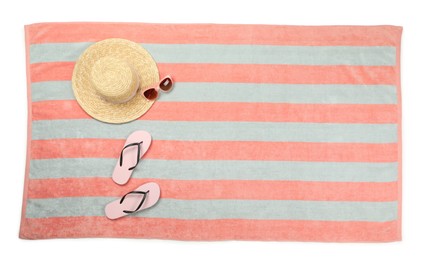 Photo of Striped beach towel with flip flops, hat and sunglasses on white background, top view