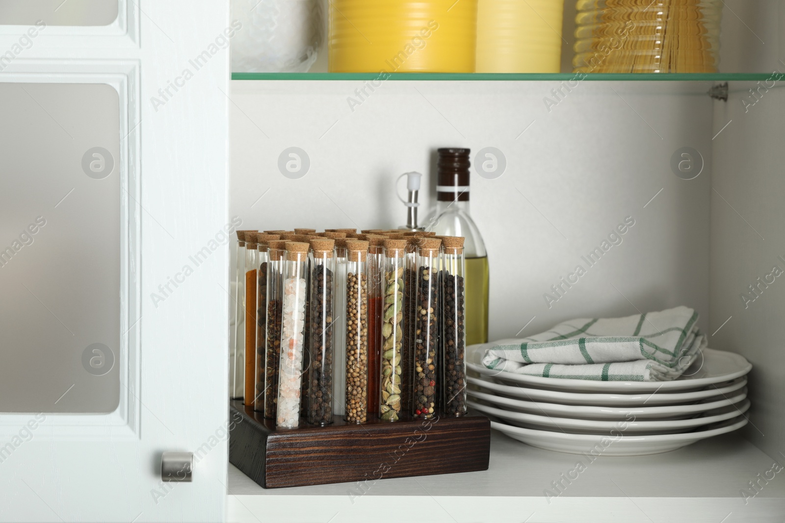 Photo of Glass tubes with different spices in kitchen cabinet