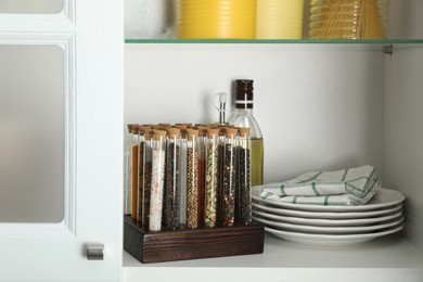 Photo of Glass tubes with different spices in kitchen cabinet