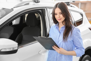 Photo of Saleswoman with clipboard in salon. Buying new car