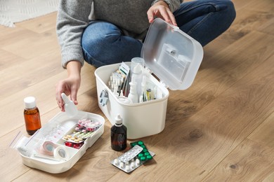 Photo of Woman putting medicament into first aid kit indoors, closeup. Space for text