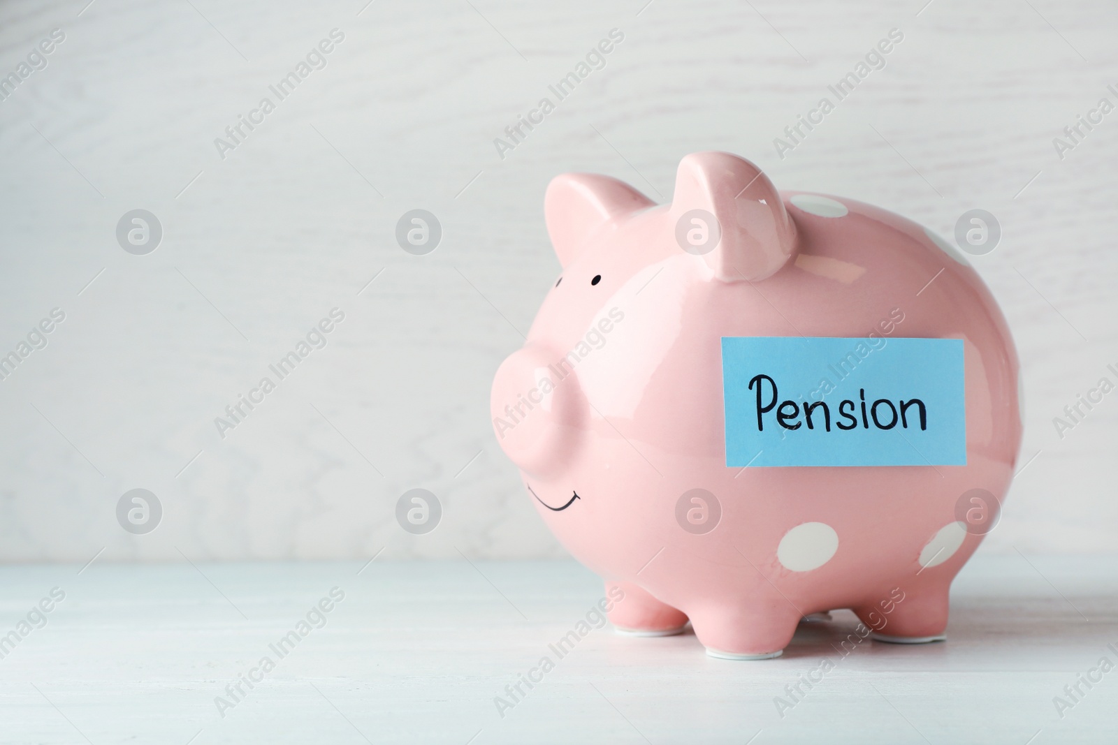 Photo of Piggy bank and paper with word PENSION on table. Space for text