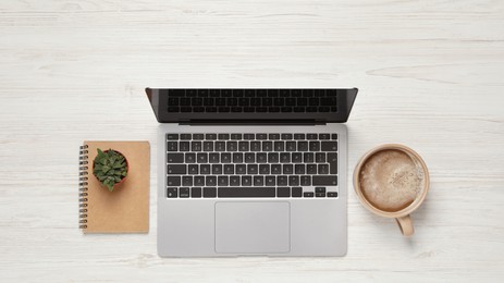 Photo of Modern laptop, houseplant, notebook and cup of coffee on white wooden table, flat lay