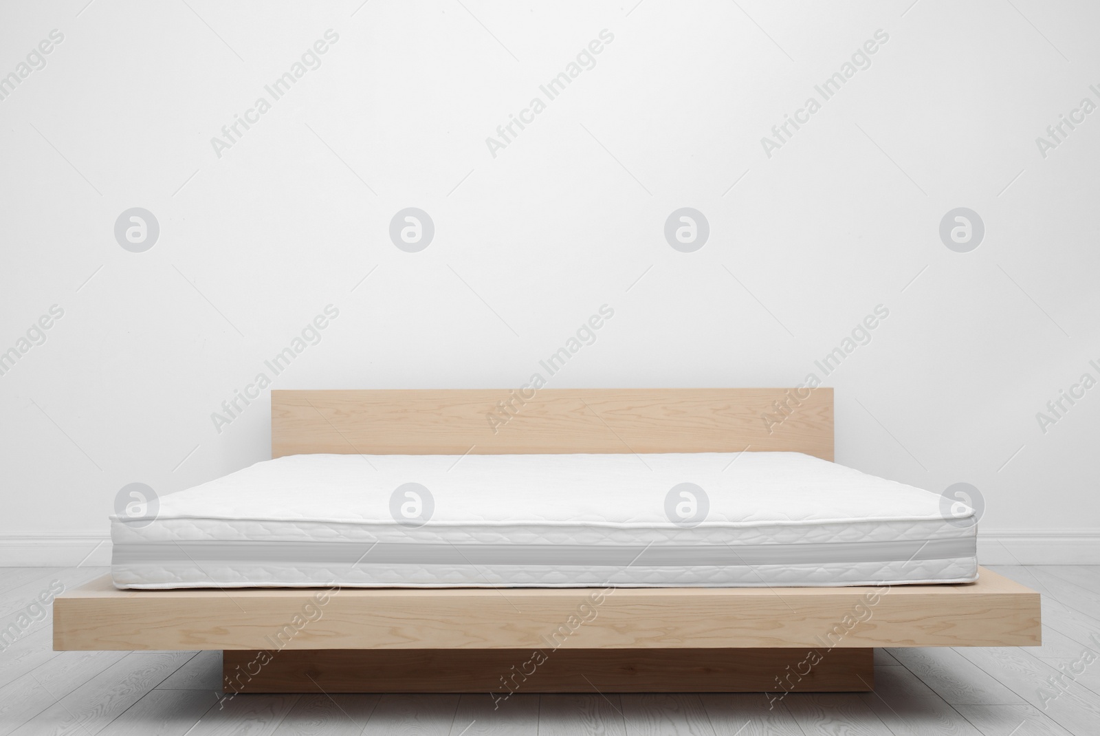 Photo of Comfortable bed with modern orthopedic mattress near white wall indoors