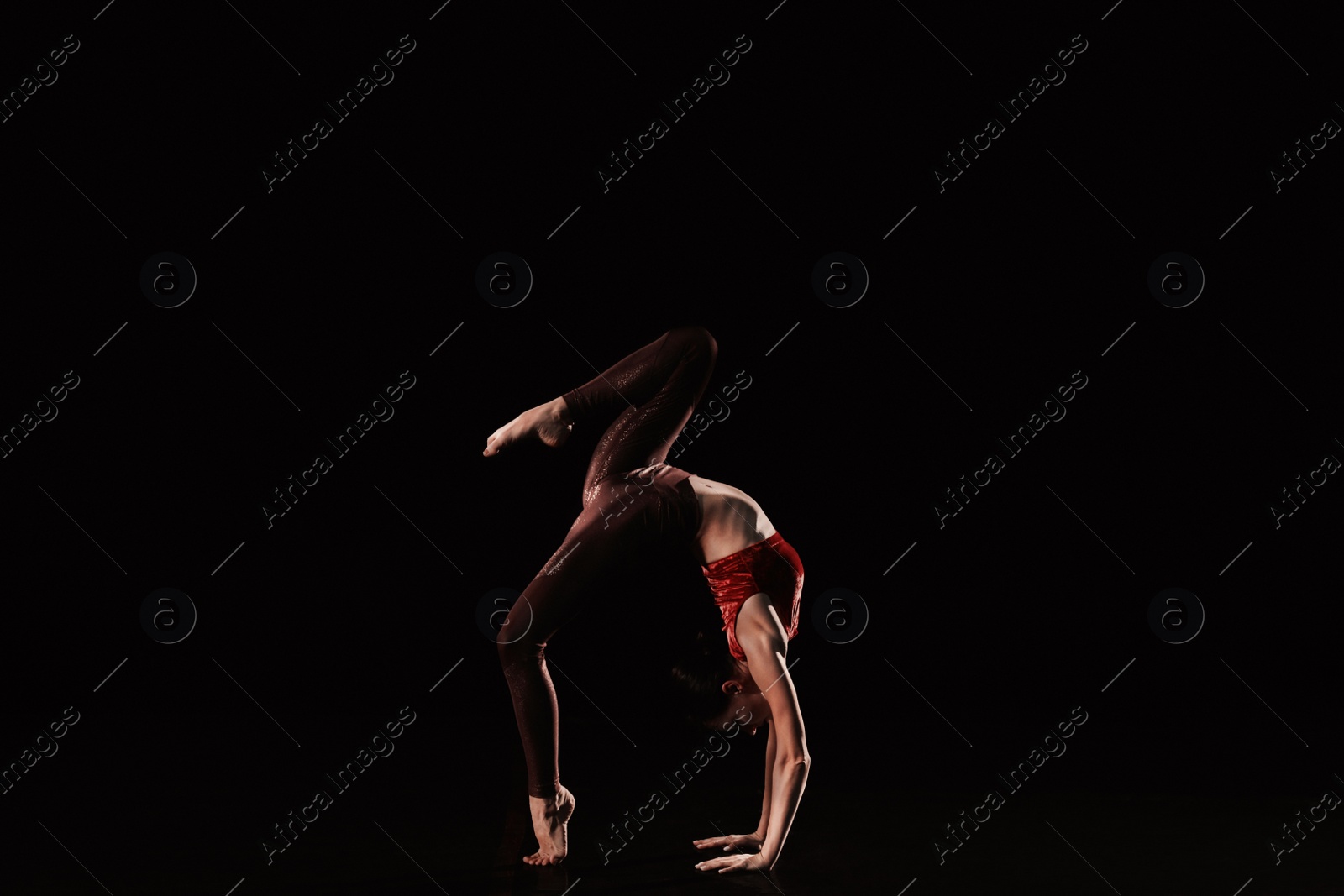 Photo of Young woman performing acrobatic element on stage indoors