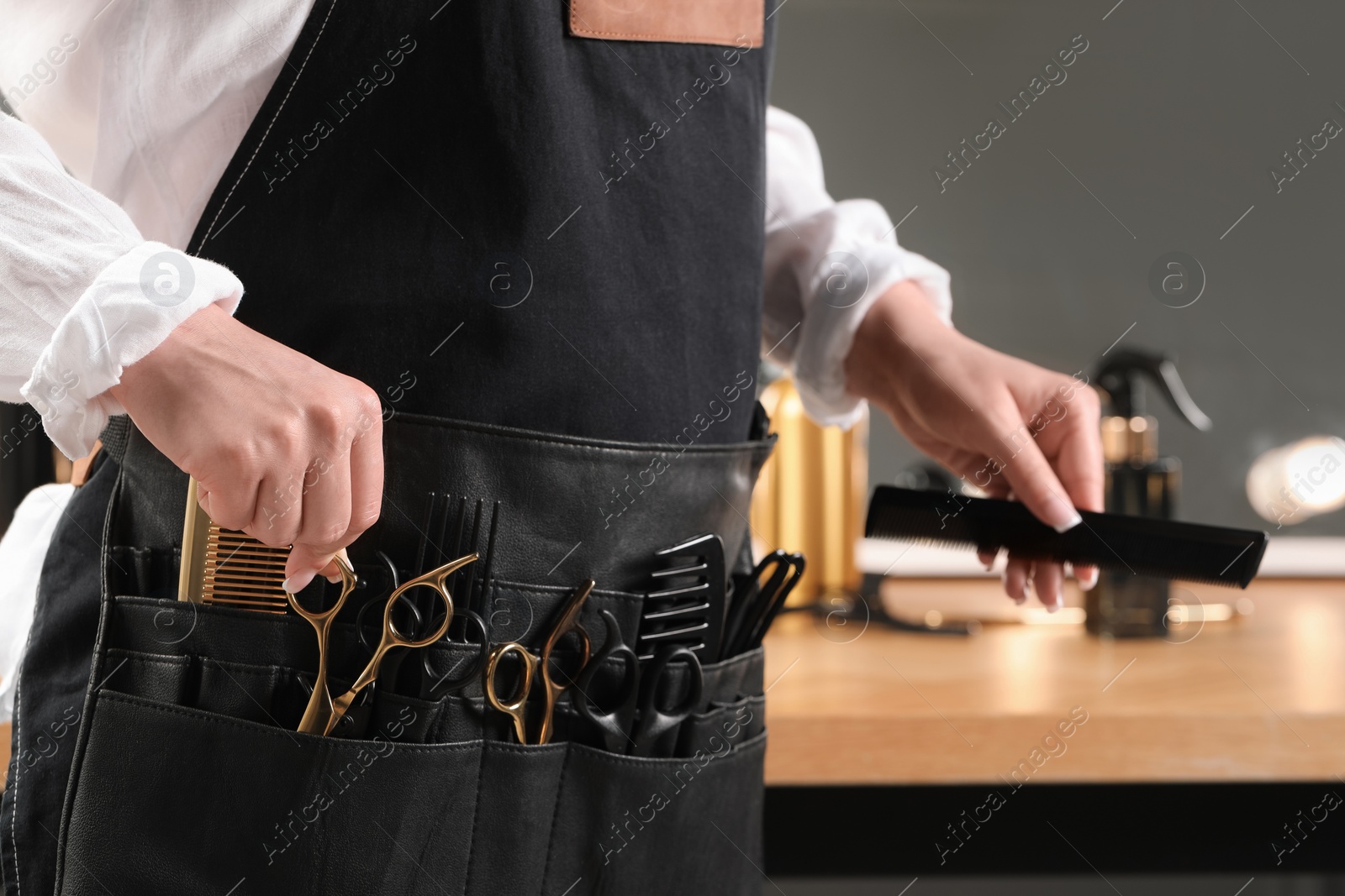 Photo of Hairstylist with professional tools in waist pouch in salon, closeup