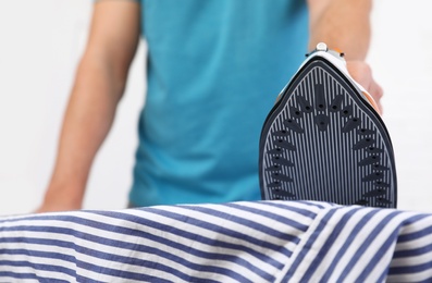 Man ironing shirt on board at home, closeup. Space for text