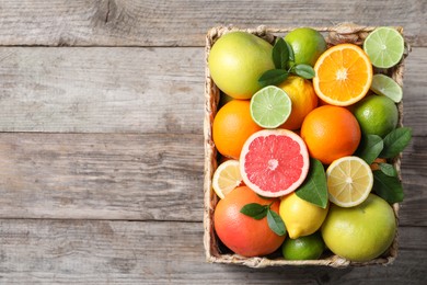 Photo of Different cut and whole citrus fruits on wooden table, top view. Space for text