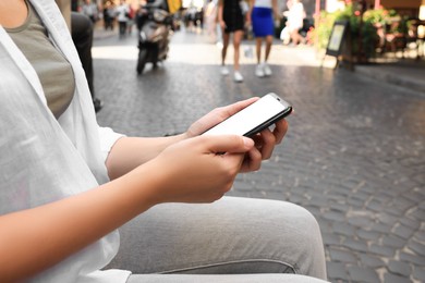 Photo of Young woman with smartphone on city street, closeup