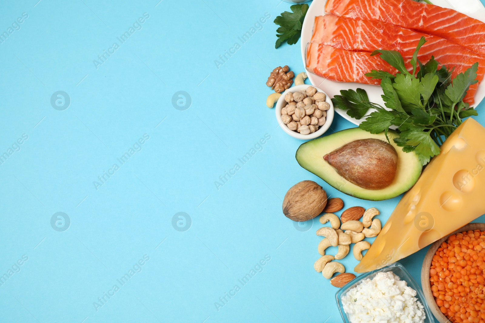 Photo of Different products rich in protein on light blue background, flat lay. Space for text