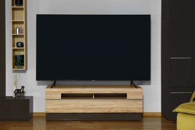 Photo of Modern plasma TV on wooden table and other furniture in living room