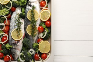 Photo of Raw fish with vegetables and lemon in baking dish on white wooden table, top view. Space for text