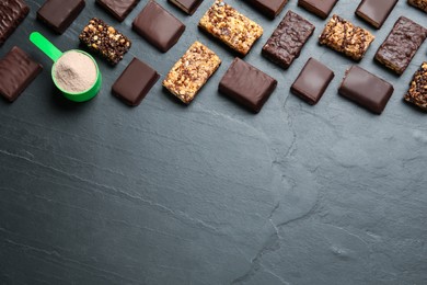 Photo of Different tasty energy bars and protein powder on black table, flat lay. Space for text