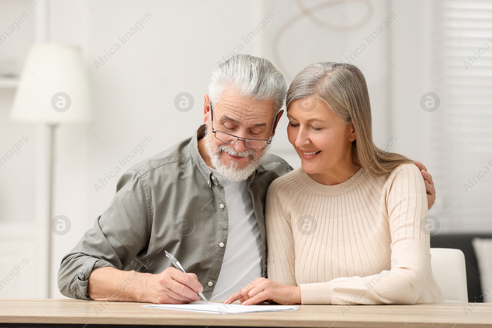 Photo of Senior couple signing Last Will and Testament indoors