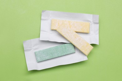 Sticks of tasty chewing gum on light green background, flat lay