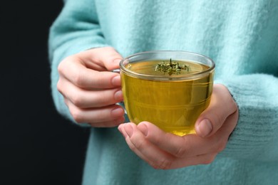 Photo of Woman holding cup of tasty herbal tea with thyme, closeup