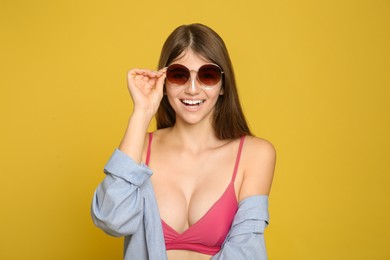 Teenage girl applying sun protection cream on her face against yellow background