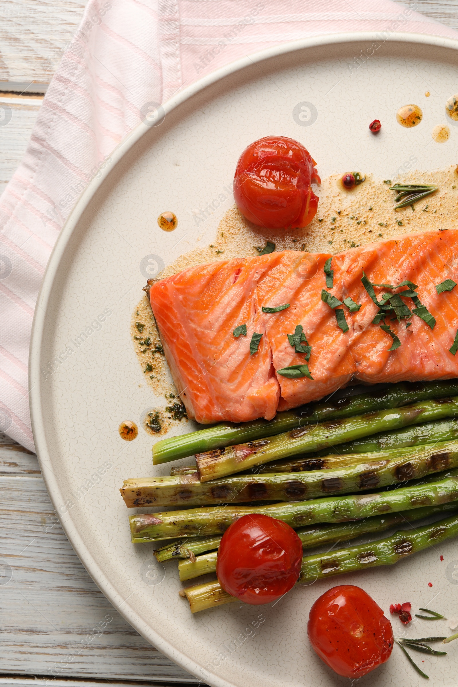 Photo of Tasty grilled salmon with tomatoes, asparagus and spices on table, top view