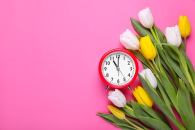 Photo of Red alarm clock and beautiful tulips on pink background, flat lay with space for text. Spring time