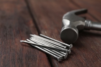 Photo of Hammer and metal nails on wooden table, closeup