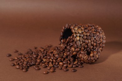 Cup made of coffee beans on brown background