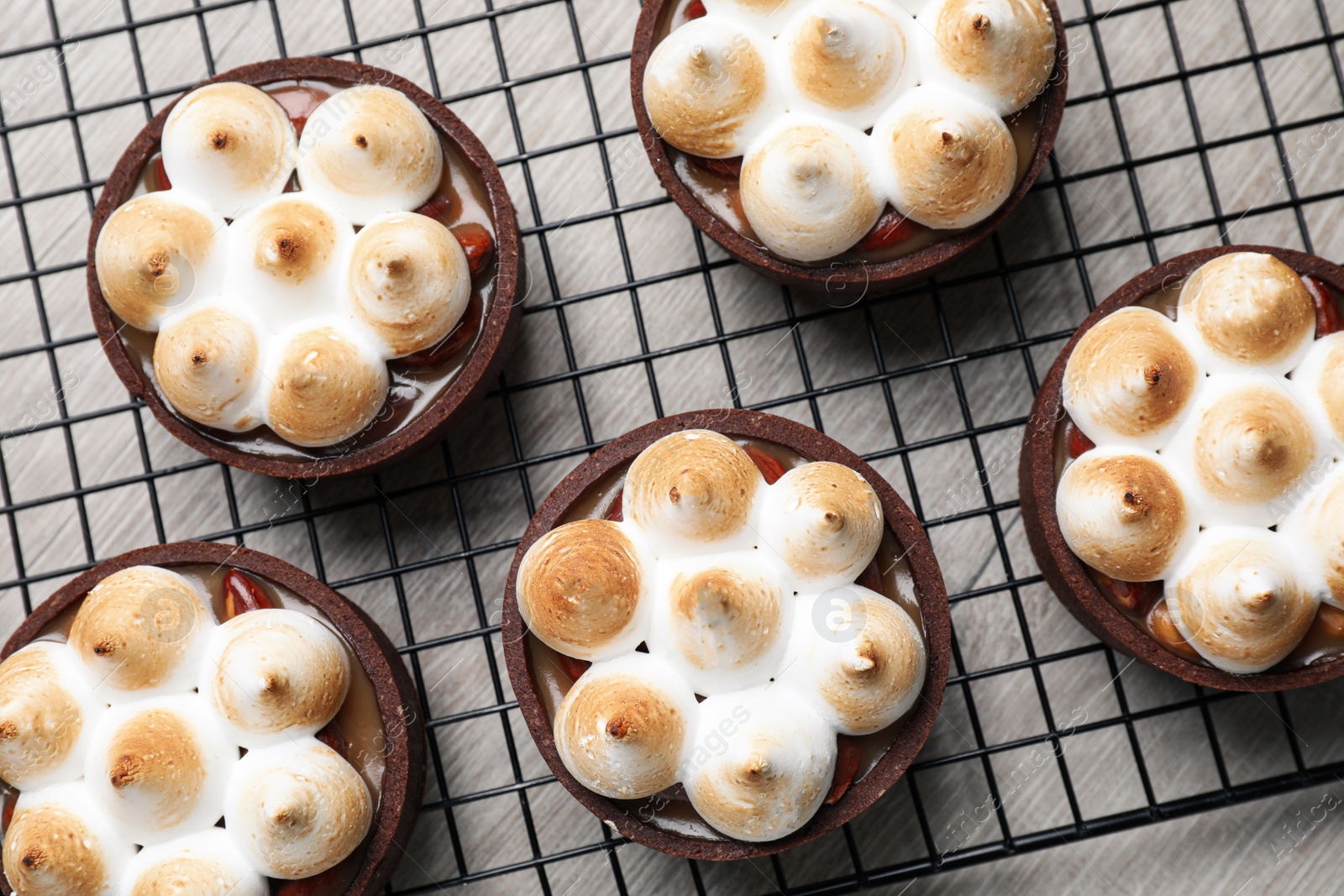 Photo of Delicious salted caramel meringue tarts on light wooden table, flat lay