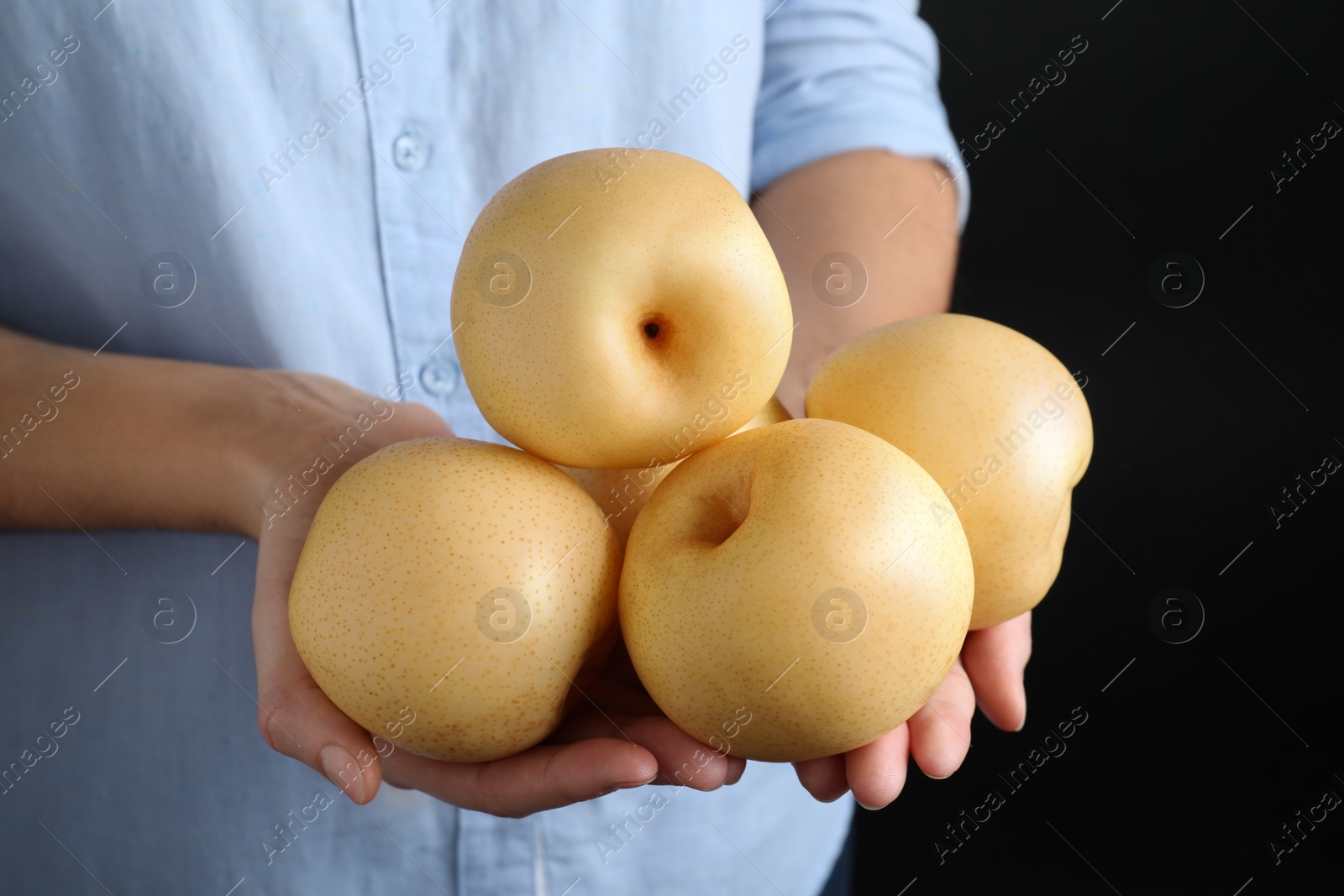 Photo of Woman holding ripe apple pears on black background, closeup