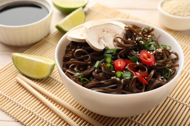 Photo of Tasty buckwheat noodles (soba) with mushrooms, onion and chili pepper served on table, closeup