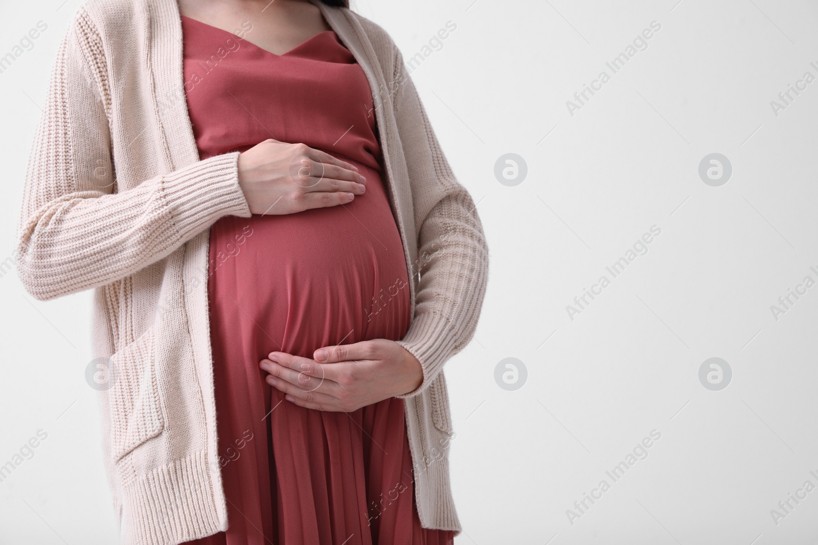 Photo of Young pregnant woman on light background, closeup. Space for text