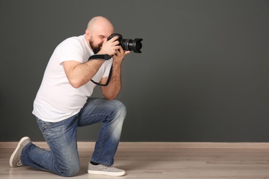 Photo of Male photographer with camera near grey wall