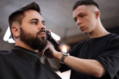 Professional hairdresser working with client in barbershop